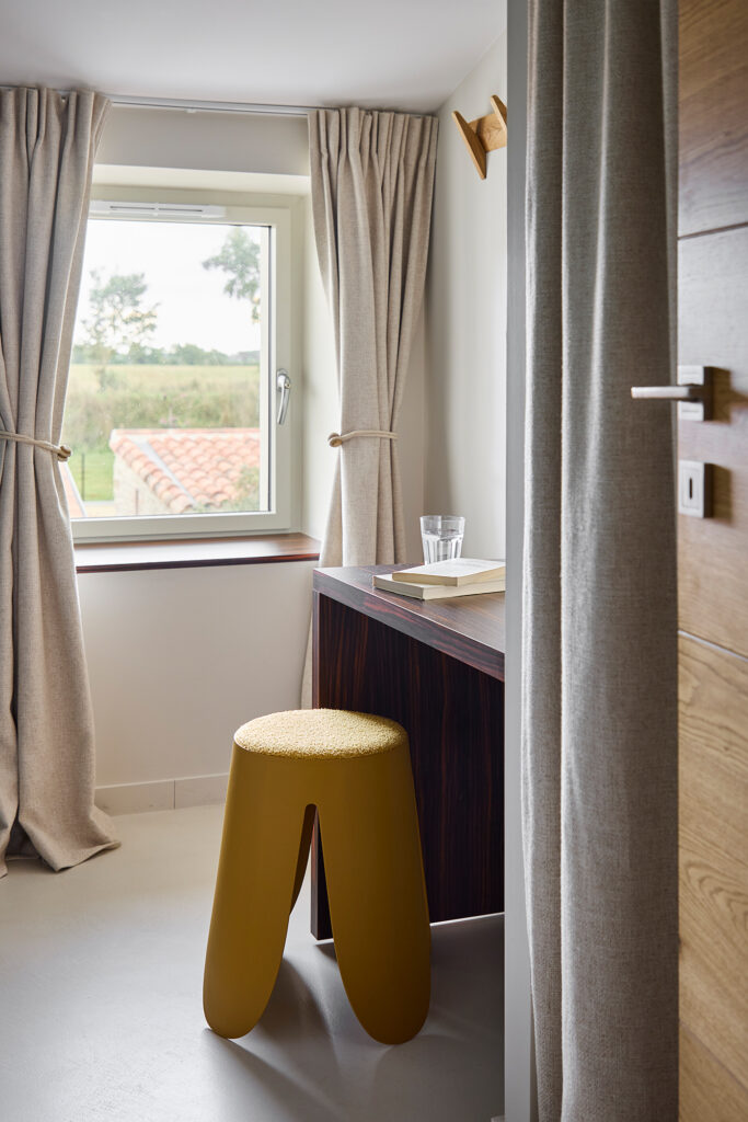 Petit bureau dans le chambre d'un gîte avec un tabouret jaune