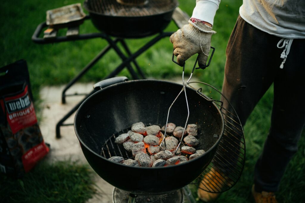 Un homme disposant du charbon dans un barbecue de la marque weber